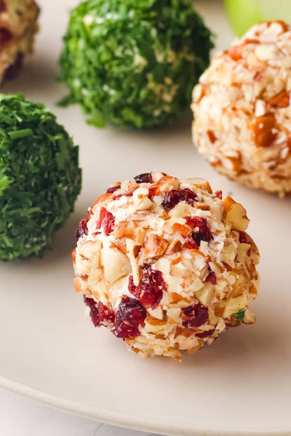 Closeup of mini cheese ball coated with chopped pecans and dried cranberries.