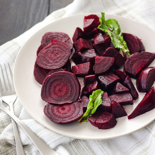 Sliced and quartered beets on a white plate.