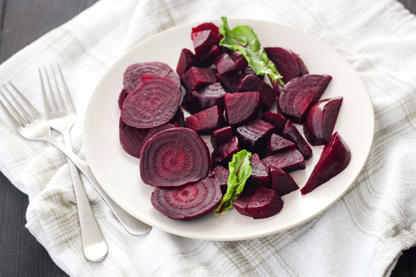 Sliced cooked beets on a white plate.