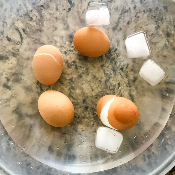 Eggs with cracked shells in a bowl of ice water.