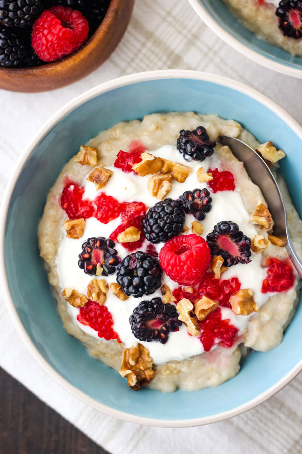 A blue bowl filled with oatmeal topped with yogurt, berries and nuts.