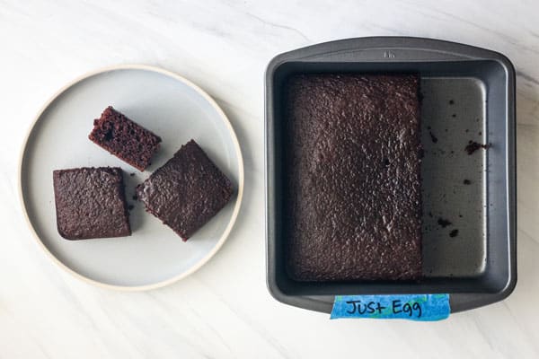 Thick slices of chocolate cake next to pan labeled with text Just Egg.