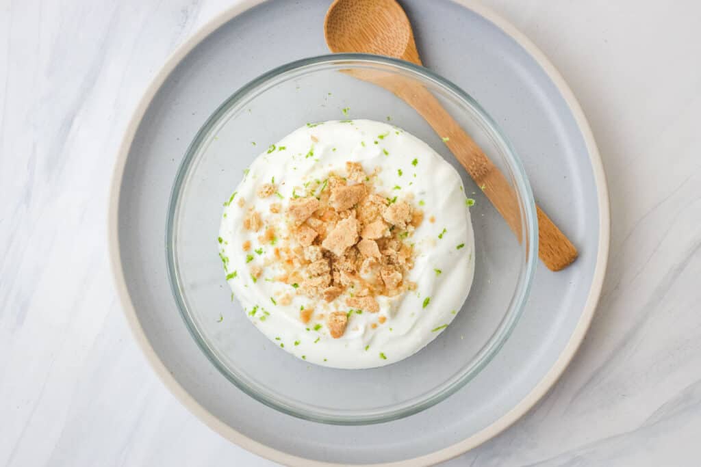 Glass bowl of yogurt with a small spoon.