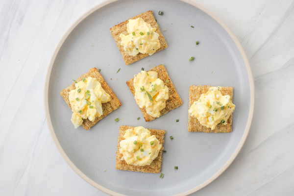 Plate of crackers topped with egg salad.