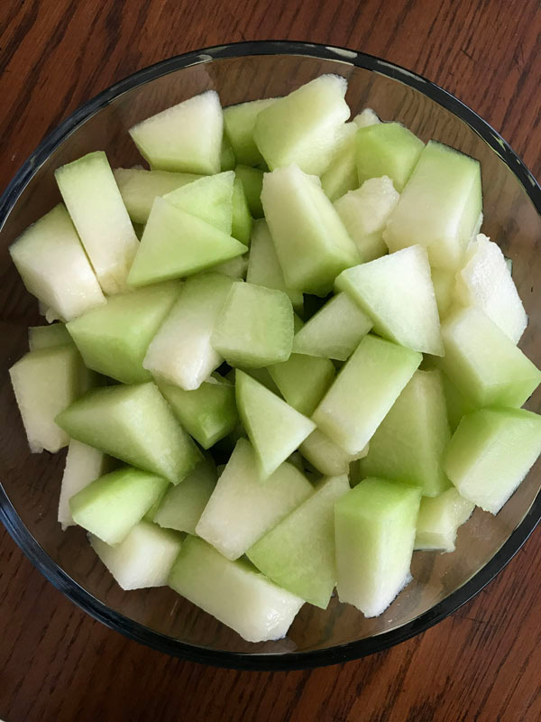 A glass bowl of chopped lemon drop melon.