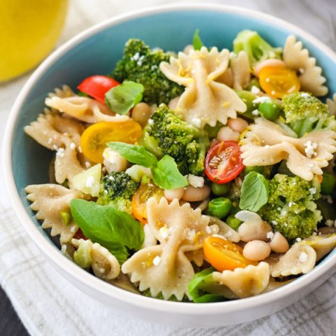 Pasta and vegetables in a blue and white bowl on a white napkin.