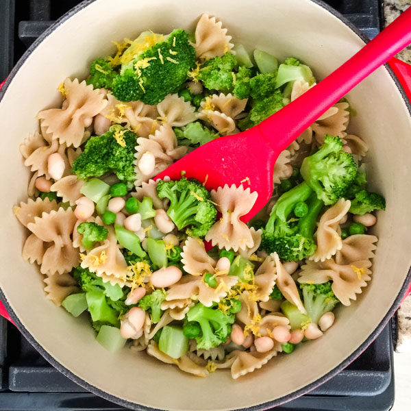 Cooked pasta and broccoli in a pot with beans and lemon zest.