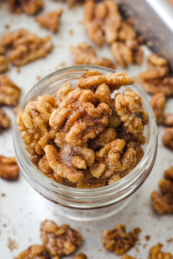 Overhead view of sparkly cinnamon walnuts in a glass mason jar. 