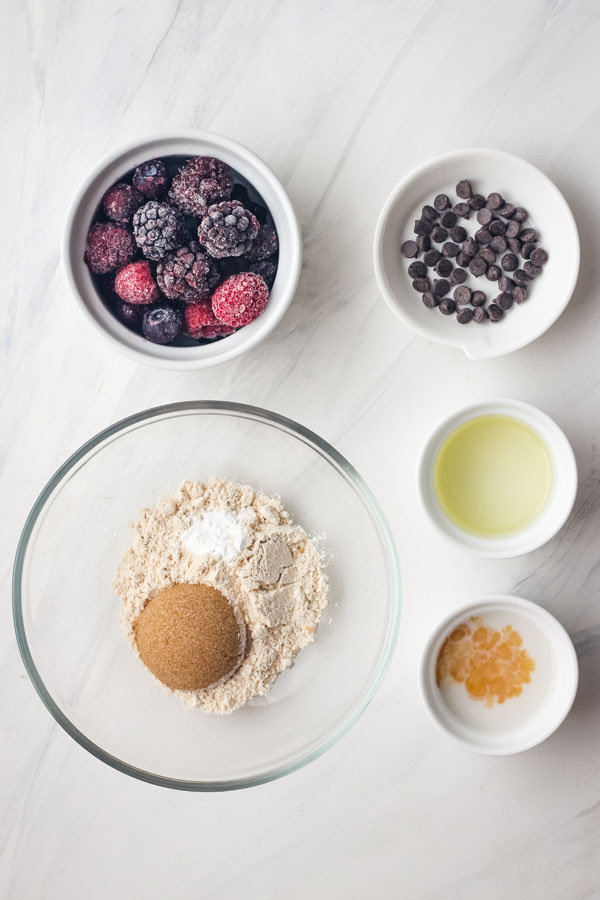 Small ramekins filled with frozen berries, oil, milk, flour, and mini chocolate chips. 