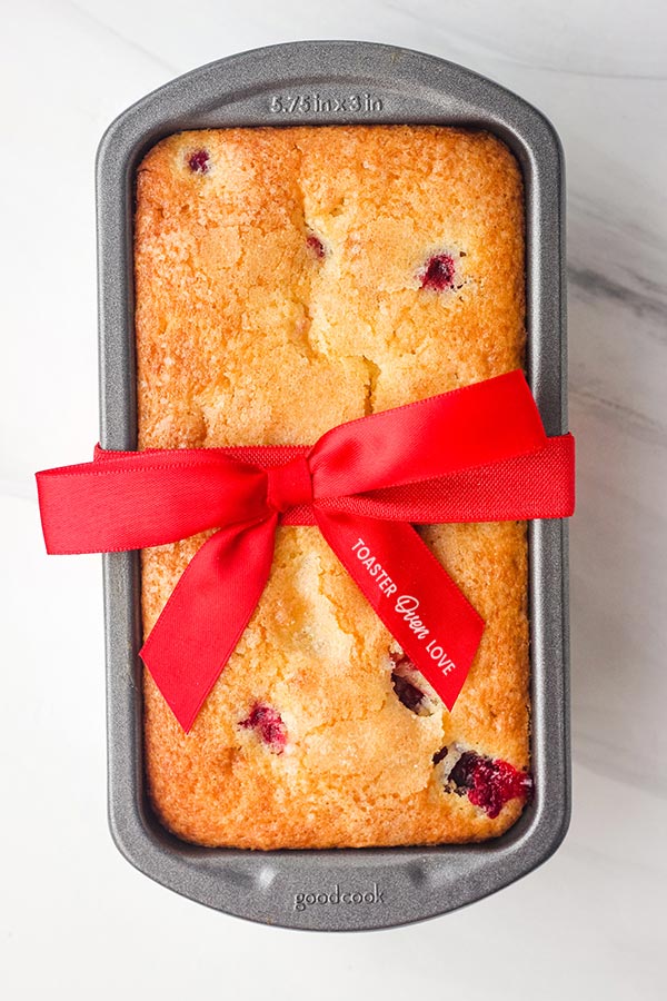 Cranberry bread in a mini loaf pan tied with a red ribbon.