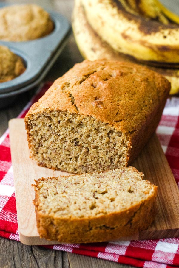 A small loaf of banana bread sliced on a mini cutting board.