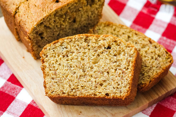 Close up of banana bread slices on a cutting board and red and white napkin.