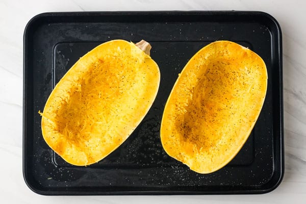 Seasoned spaghetti squash on a roasting pan.