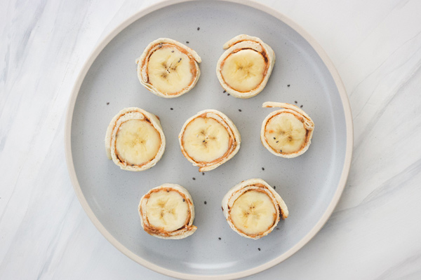 Blue plate with peanut butter banana pinwheels.