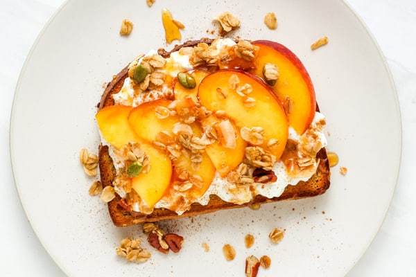 Peach slices with granola on cottage cheese toast.