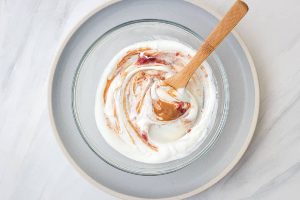 Bowl of yogurt with swirls of peanut butter and jelly.