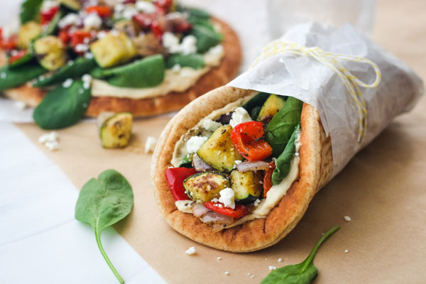 Pita sandwiches wrapped in parchment paper and tied with a string.