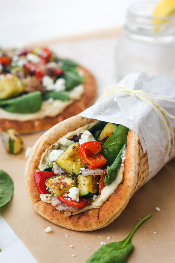 A veggie pita wrapped in a piece of parchment and tied with yellow and white string.