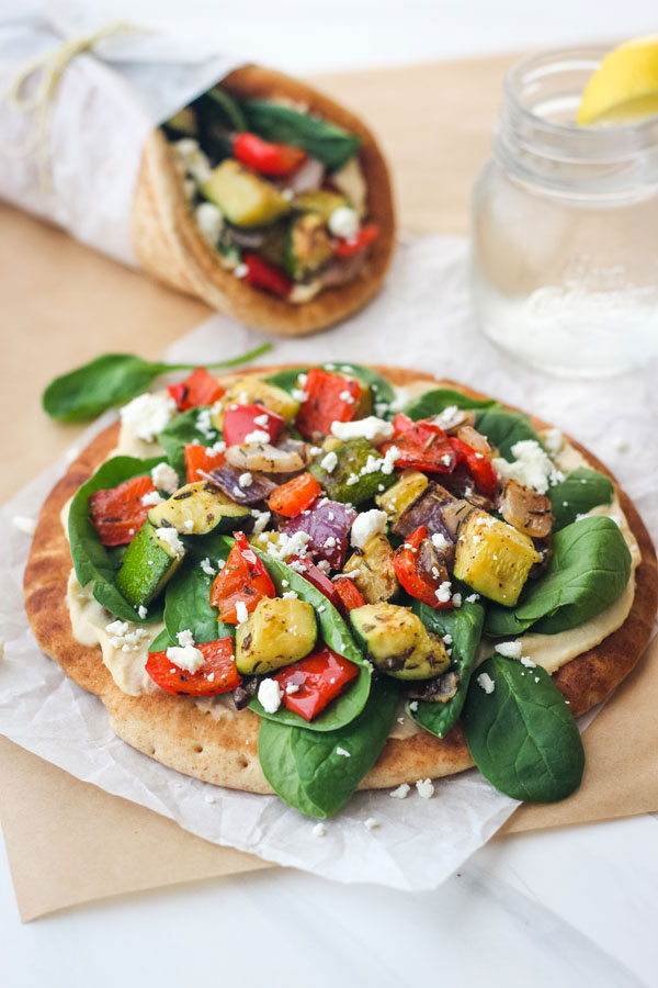 Layered veggie and hummus pita on a piece of parchment paper.