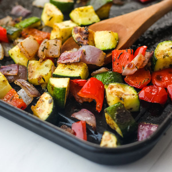 Roasted vegetables on a dark roasting pan.