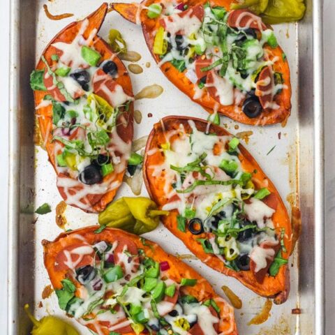 A quarter sheet pan with four topped pizza sweet potatoes.