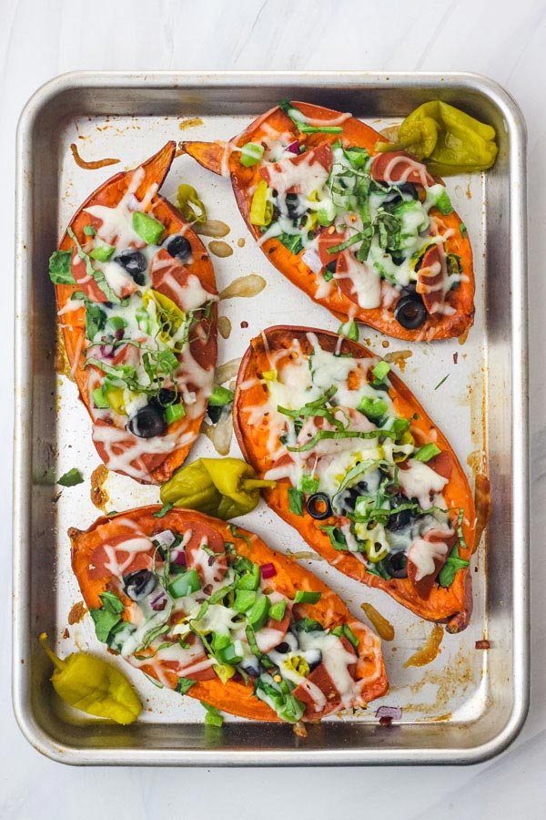 A quarter sheet pan with four topped pizza sweet potatoes.