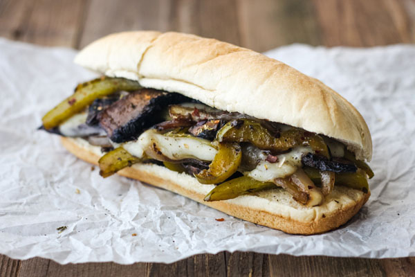 Sideview of melted cheese, peppers, and mushroom in a sandwich roll.