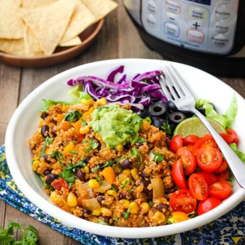 A white bowl with Mexican quinoa on a table with an instant pot mini.