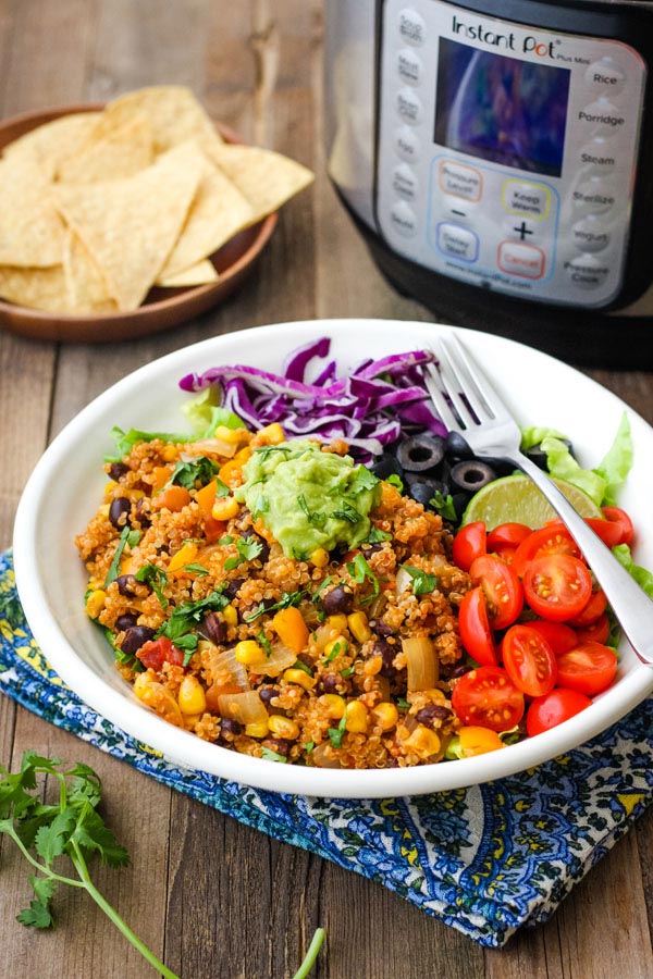 A white bowl with Mexican quinoa on a table with an instant pot mini.