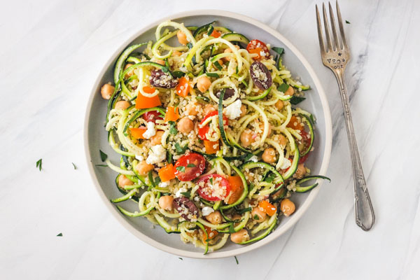 Salad on a blue plate with a fork stamped with "veg out".