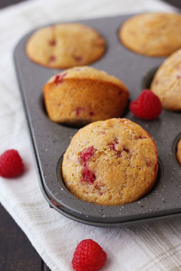 Raspberry lemon corn muffins cooling in a muffin pan.