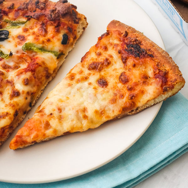 Closeup of melty cheese pizza slice on a plate.