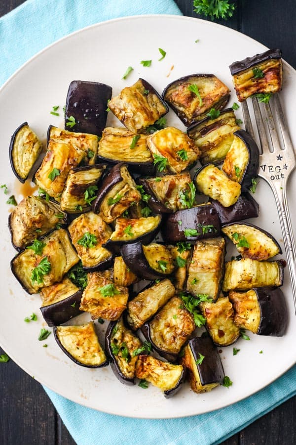 Roasted eggplant on a plate with fork stamped with veg out text.