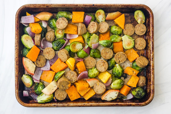 A quarter sheet pan with vegetarian sausage and par-roasted vegetables.