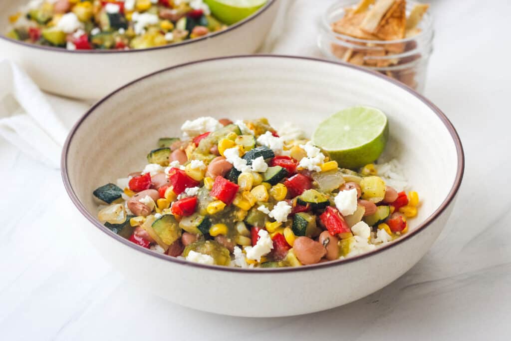 Bowl of rice topped with salsa and colorful roasted vegetables.