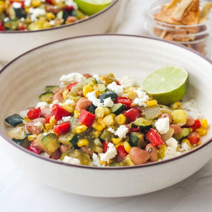 Bowl of rice topped with salsa and colorful roasted vegetables.