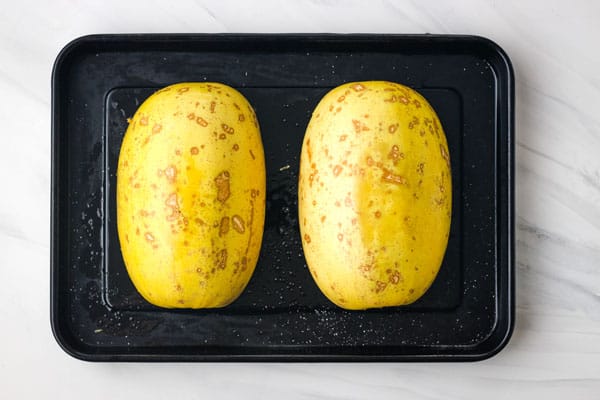 Spaghetti squash on a dark roasting pan.