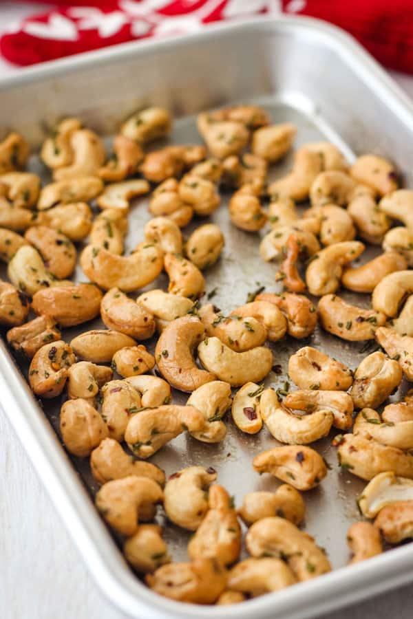 Red oven mitt and 1/8 sheet pan of cooked nuts on a white table.