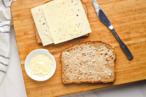 Bread slices topped with cheese on a cutting board.