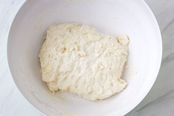 Overhead view of shaggy and sticky dough in a bowl.