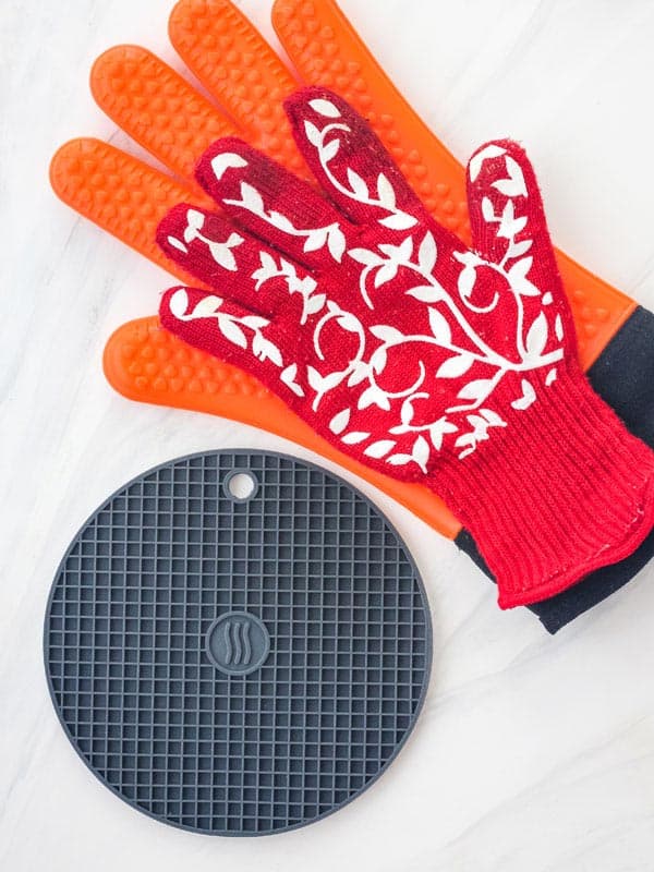 Small gray silicone trivet and bright red and orange silicone oven gloves.