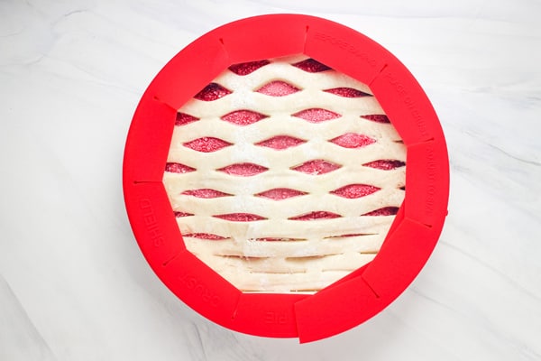 Overhead view of pie with a red silicone pie shield wrapped around the edges.