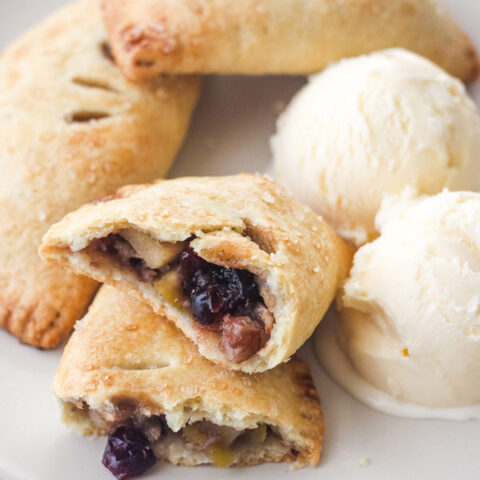 Hand pies on a plate with scoops of vanilla ice cream.