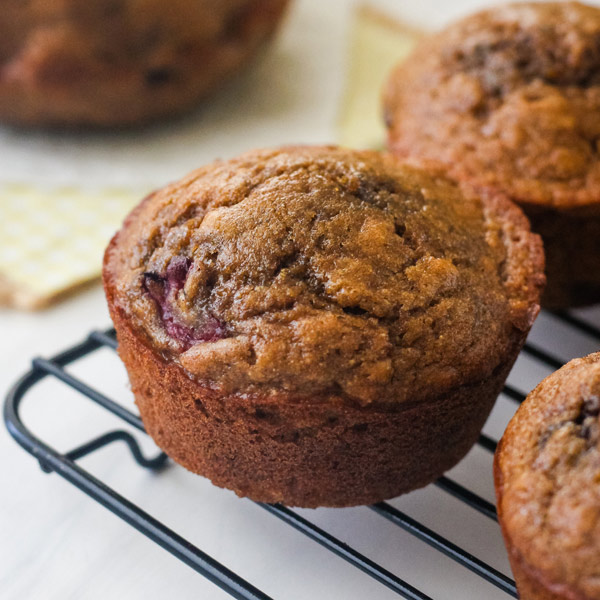 Closeup of a banana berry muffin on a black cooling rack.