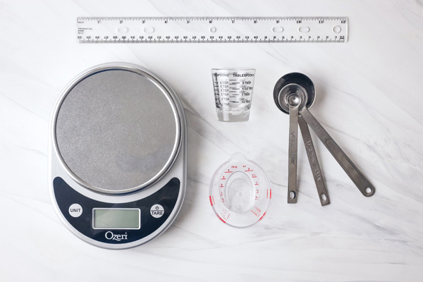 Digital scale, mini liquid measuring cups, small measuring spoons, and a plastic ruler.