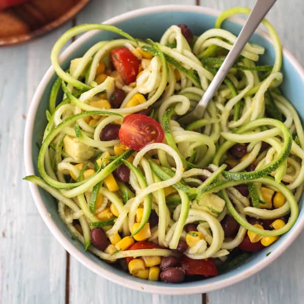 Tossed southwestern zucchini noodle salad in a small blue bowl.