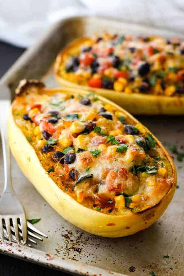 Two spaghetti squash boats on a metal sheet pan with two forks.