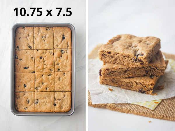 A small baking pan next to a stack of cookie bars on parchment.