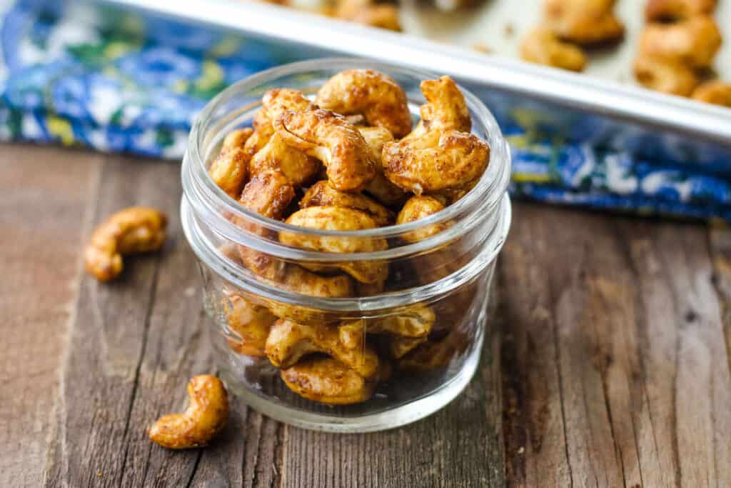 Closeup of seasoned cashews in a small mason jar.