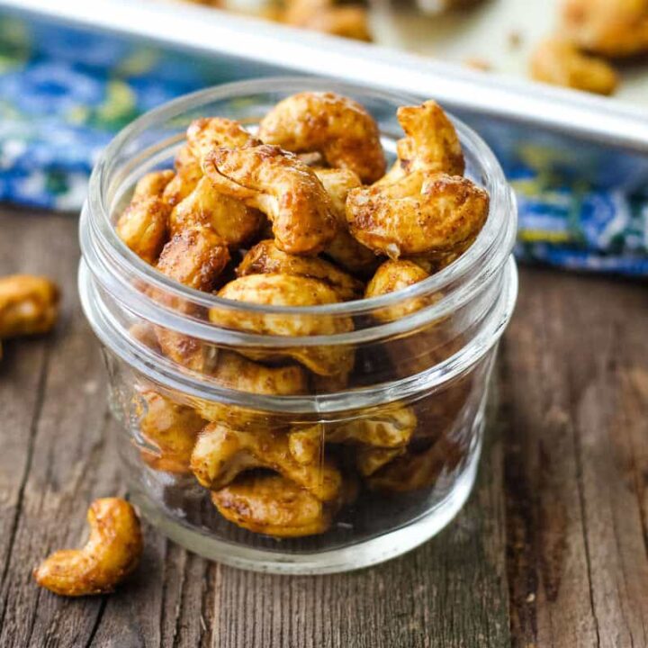 Closeup of seasoned cashews in a small mason jar.